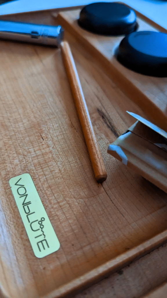 Nahaufnahme der Mischefläche des VONbLÜTE Chill One Rolling Tray aus Kirschholz mit feiner Maserung, Messinglogo, Stopfstab & Kingsize-Papers.