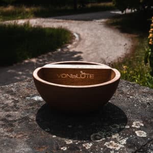 The Bowl Mischeschale aus Eichenholz mit Edelstahl-Logo, inszeniert im sommerlichen Naturambiente