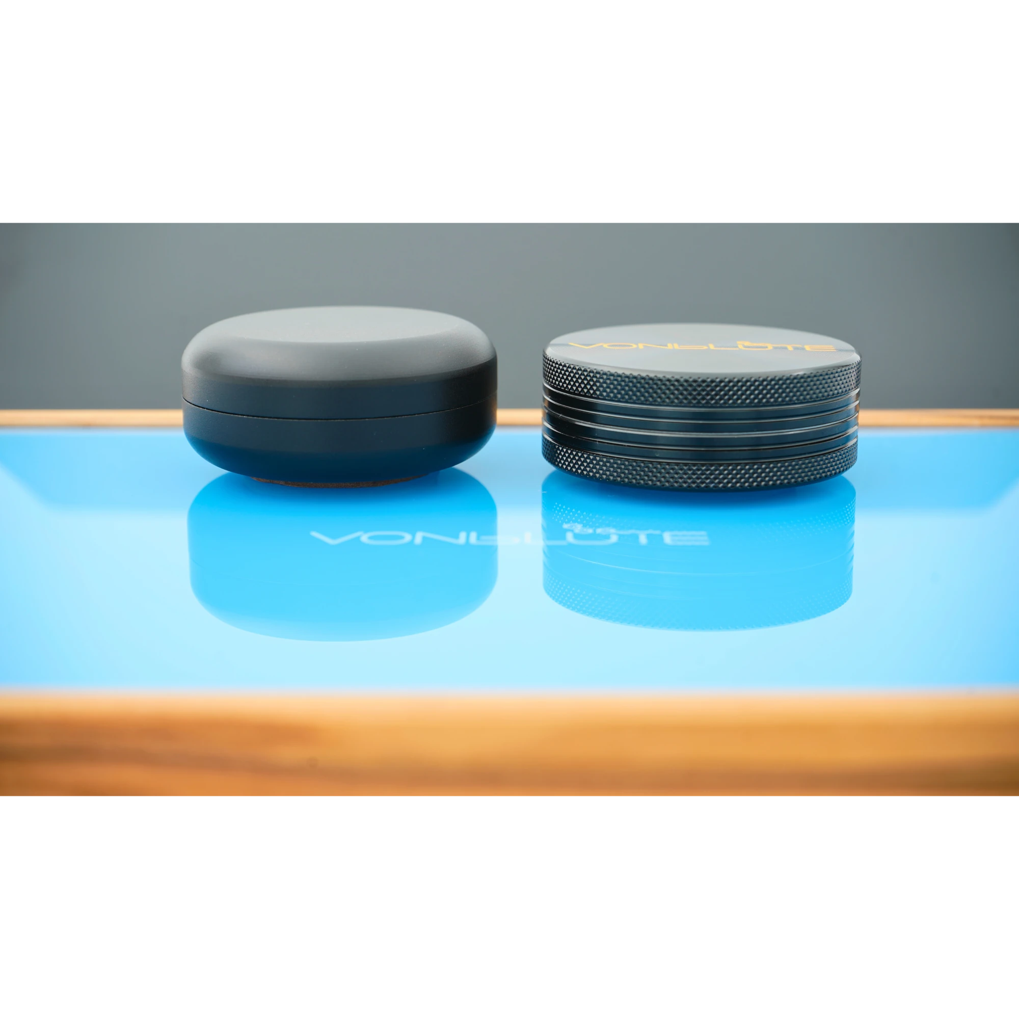 Rolling Tray Float Red Tone Sky Blue Edition Black darstellung des schwebenden design effektes auf der hellblauen Glasscheibe, demonstriert an schwarzem Grindner und Dose.