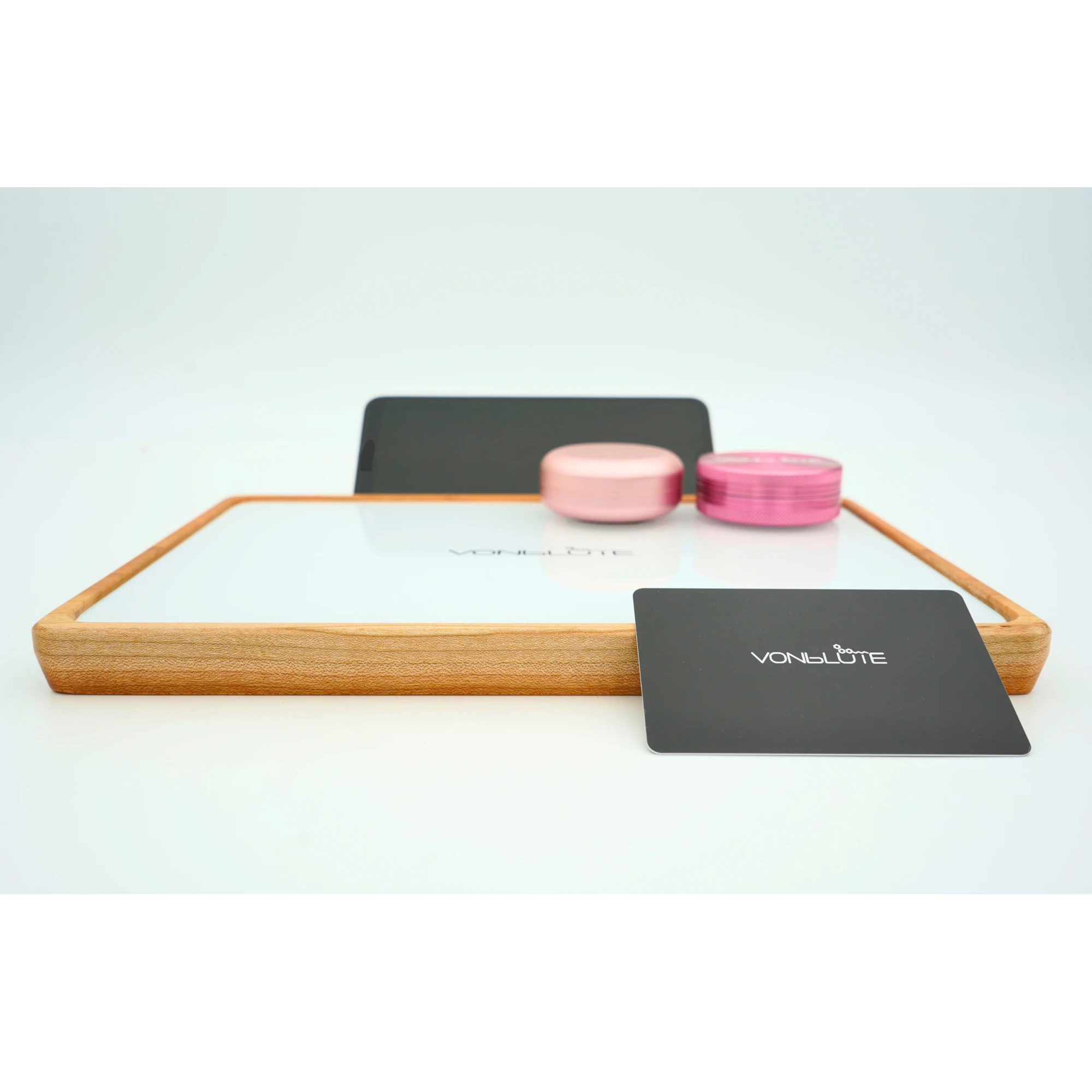 Rolling Tray Float Red Tone Weiss Edition Pink Frontal mit adaptiertem Smartphone und Zubehör in Pink. Eine Pinke Dose und ein pinker Grinder liegen auf, an der Front lehnt die Mischkarte in schwarz.